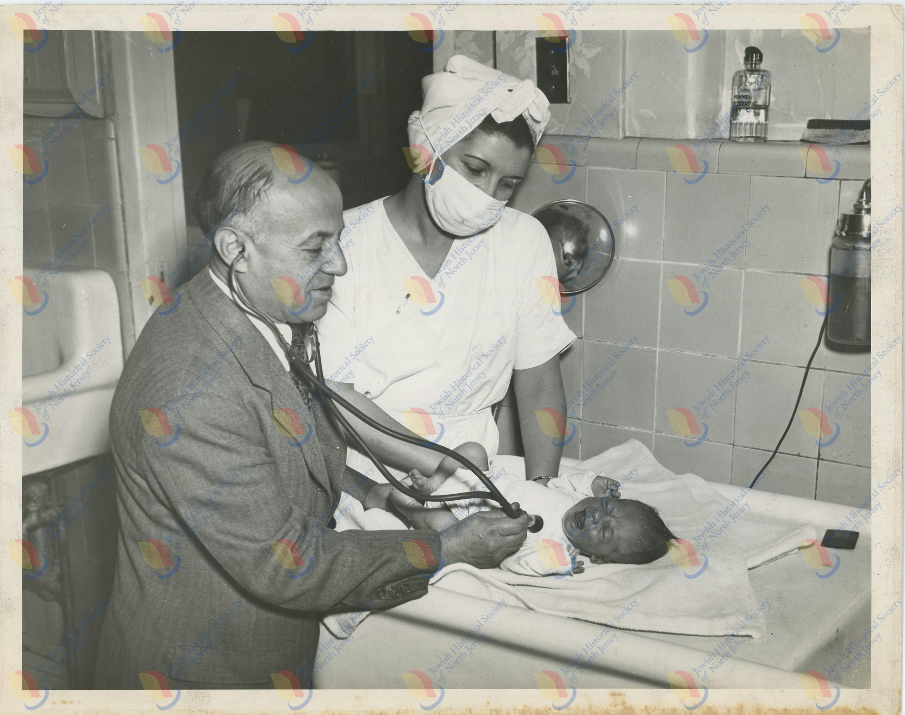 Photo by Simpson Studio - Dr. Morris S. Joelson examining a baby with a nurse.